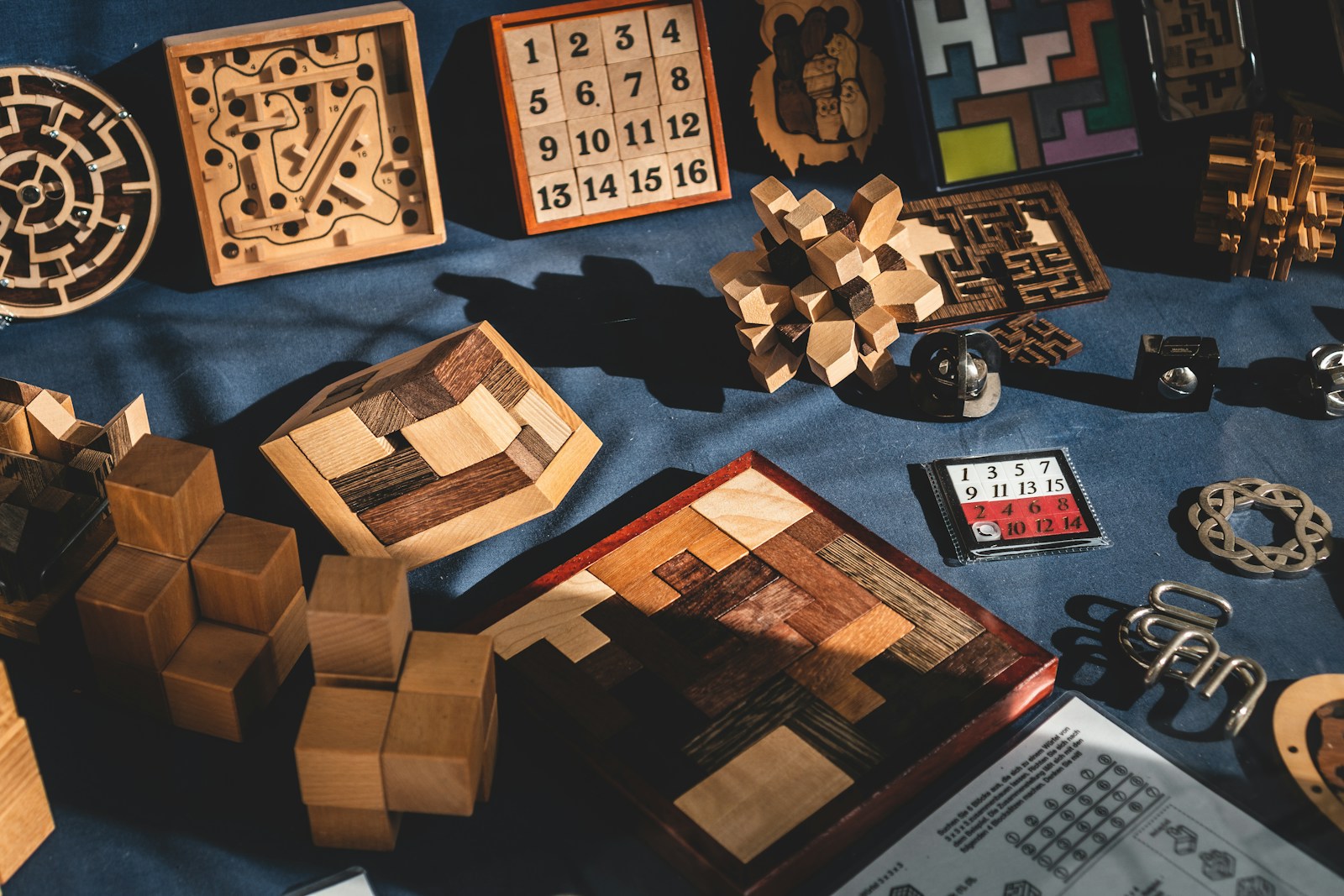 Wooden number puzzles, mazes and interlocking brain teasers arranged on blue fabric